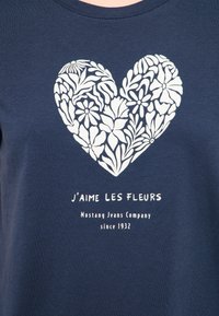 Námořnická modrá tričko s bílým květinovým srdcem, pod nímž je text "J'aime les Fleurs" a "Mustang Jeans Company since 1932".