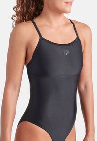 Costume da bagno nero con spalline sottili, realizzato in tessuto liscio. Presenta un logo sul petto e un design aderente per un movimento snodato.