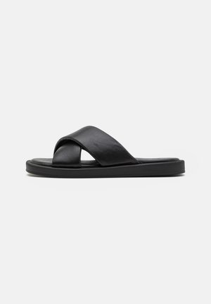 Black leather slide sandal with a cross-strap design, flat sole, and smooth texture. Minimalist style without prominent patterns or hardware.