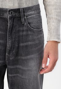 Grijze denim jeans met een vervaagde afwerking, vijf-pocket ontwerp, knoopsluiting en stiknaadaccenten op de zakken en naden.