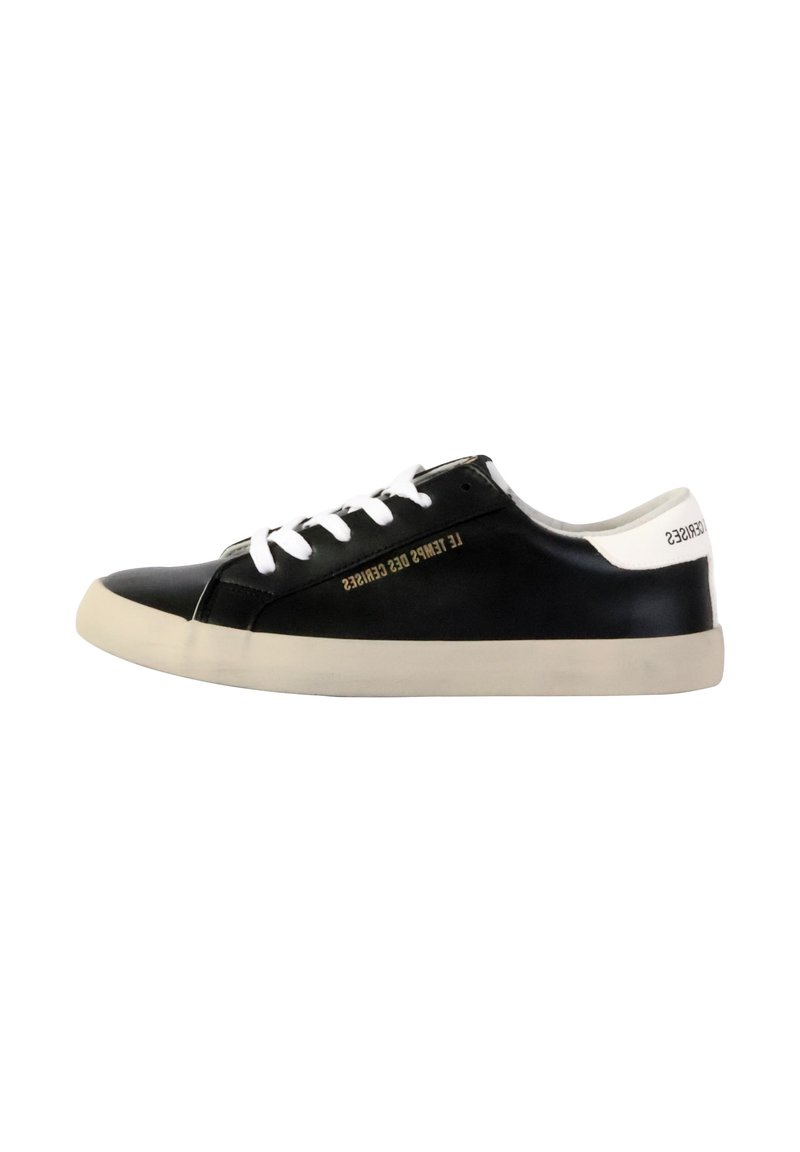 Zapatilla negra de cuero con cordones blancos y talón blanco, que presenta una suela de goma texturizada y un detalle de texto dorado en el lateral.