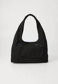 Sort canvas skuldertaske med en rund form, en stor åbning og en frontlomme med lynlås. Blød tekstur uden synlige mønstre.