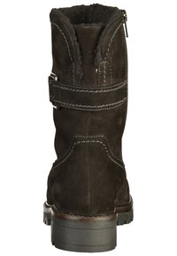 Stivaletto alla caviglia in suede marrone scuro con superficie textured, cuciture decorative e cerniera laterale. Presenta un tacco spesso e robusto e un accento a tracolla.