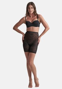 Svarta, genomskinliga högmidjade shorts med blommönster och slät midja. En tornado-liknande textur med en åtsittande design som sträcker sig till mitten av låret.