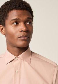 Rosa Hemd mit Knopfleiste, strukturiertem Kragen, glatter Textur und dezentem Glanz. Verfügt über eine durchgehende Knopfleiste vorne und eine taillierte Passform.