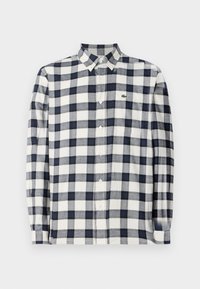 Gestructureerde langwerpige blouse in marineblauw en wit, gemaakt van zachte stof, met een knoopsluiting en een klein logo op de borst.