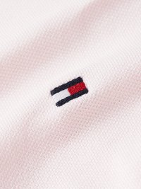 Tecido rosa claro com textura canelada, apresentando um pequeno logótipo bordado em riscas vermelhas, brancas e azuis marinho no canto inferior direito.