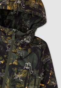 Zielona kurtka przeciwdeszczowa w wzory, z zapięciem na zamek, kapturem oraz nadrukiem dinozaurów i zabawnym tekstem. Materiał ma gładką teksturę.