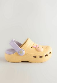 Sabot moulé jaune avec une sangle lavande et une décoration en forme de lapin à l'avant. Présente des trous de ventilation et une semelle texturée.