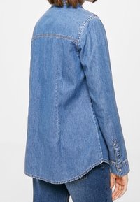 Lichtblauwe denim shirt met een button-down kraag, lange mouwen en een gebogen zoom. Kenmerkt zich door contrasterende stiksels en een ontspannen pasvorm.