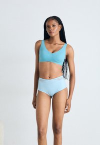 Világoskék sportmelltartó V-nyakú kivitelben, széles pántokkal, amelyhez illő, magas derekú bikini alsó tartozik, texturált derékkal.