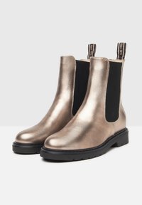 Bottines Chelsea en bronze métallique avec des panneaux latéraux élastiques noirs, finition texturée, languettes en boucle et semelles noires durables.