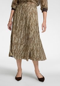 Gonna midi marrone e crema con stampa leopardata, realizzata in un tessuto leggero e fluido. Vita elastica e dettaglio con spacco laterale.