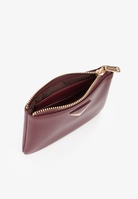 Portafoglio in pelle bordeaux con zip e elementi metallici dorati, caratterizzato da una superficie testurizzata e da una fodera interna, angolato per una migliore visibilità.