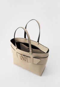 Borsa tote in pelle beige con accenti neri, forma rettangolare, doppio manico e un grande dettaglio del logo sul davanti. Interno foderato in nero.