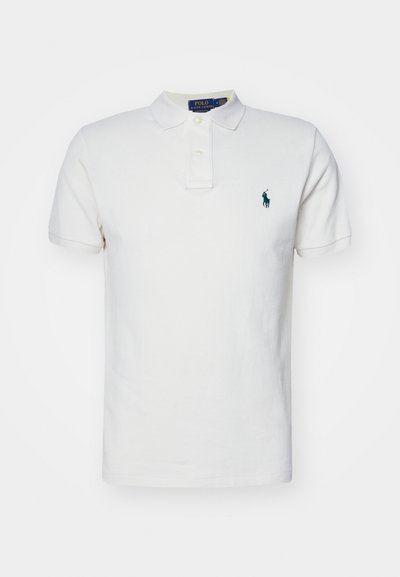Bela polo majica iz bombaža, s klasičnim ovratnikom, kratkimi rokavi in zelenim vezenim logotipom na levem prsnem delu.