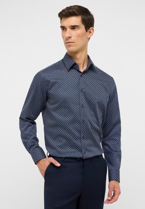 Dunkelblaues Hemd mit Knöpfen, klein gemustert mit weißen geometrischen Mustern, lange Ärmel, klassischer Kragen und kontrastierenden Knöpfen. Glatte Stofftextur.