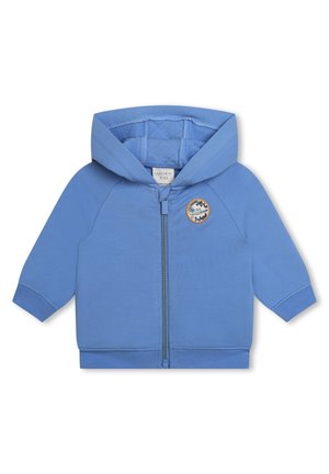 Felpa con zip di colore blu chiaro realizzata in tessuto morbido. Presenta un interno trapuntato, polsini a coste e una toppa rotonda sulla parte anteriore con un design di montagna.
