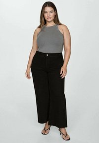 Gray ribbed tank top with sleeveless design paired with high-waisted black wide-leg jeans. The jeans have a raw hem and subtle stitching.