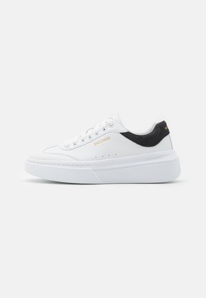 Białe niskie sneakersy z grubą podeszwą, czarnym akcentem na pięcie, białymi sznurówkami i złotym logo "SKECHERS" na boku i pięcie.
