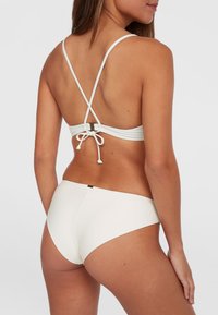 Top bikini bianco con design a incrocio e laccio regolabile sul retro; fondo bikini bianco abbinato con copertura minima.