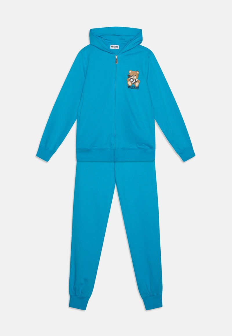 Conjunto de chándal turquesa que incluye una sudadera con cremallera con un parche gráfico de un oso y pantalones a juego, ambos en una tela suave y elástica.