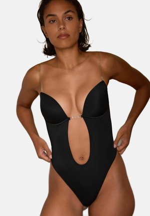 Maillot de bain une pièce noir avec un décolleté en V profond, des bretelles transparentes et une couverture minimaliste, mettant en avant un accent en métal brillant au centre.