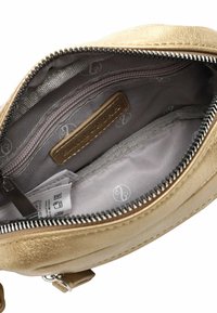 Zlatá metalická kabelka na zaklapnutí s žebříkovým uzávěrem, béžově podšívkovaným interiérem s kapsou na sklápění a vnitřním štítkem značky.