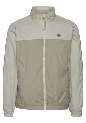 Chaqueta ligera y resistente al agua en beige y gris claro. Cuenta con un cuello alto, cierre frontal completo, puños elásticos y bolsillos laterales.