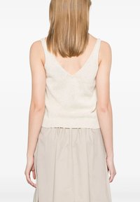 Top senza maniche avvitato di colore crema con scollatura a V e orlo rigato. Tessuto leggero con una gonna beige chiaro.