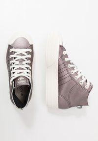 Höga sneakers i metallgrått tyg med vita skosnören och sula. Sidan har vertikal sömnad och en ögla för enklare påtagning.