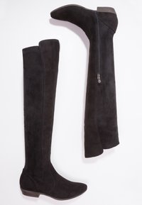 Botas de ante negras sobre la rodilla con punta afilada, un tacón cuadrado de altura media y un detalle de cremallera lateral para facilitar su uso.