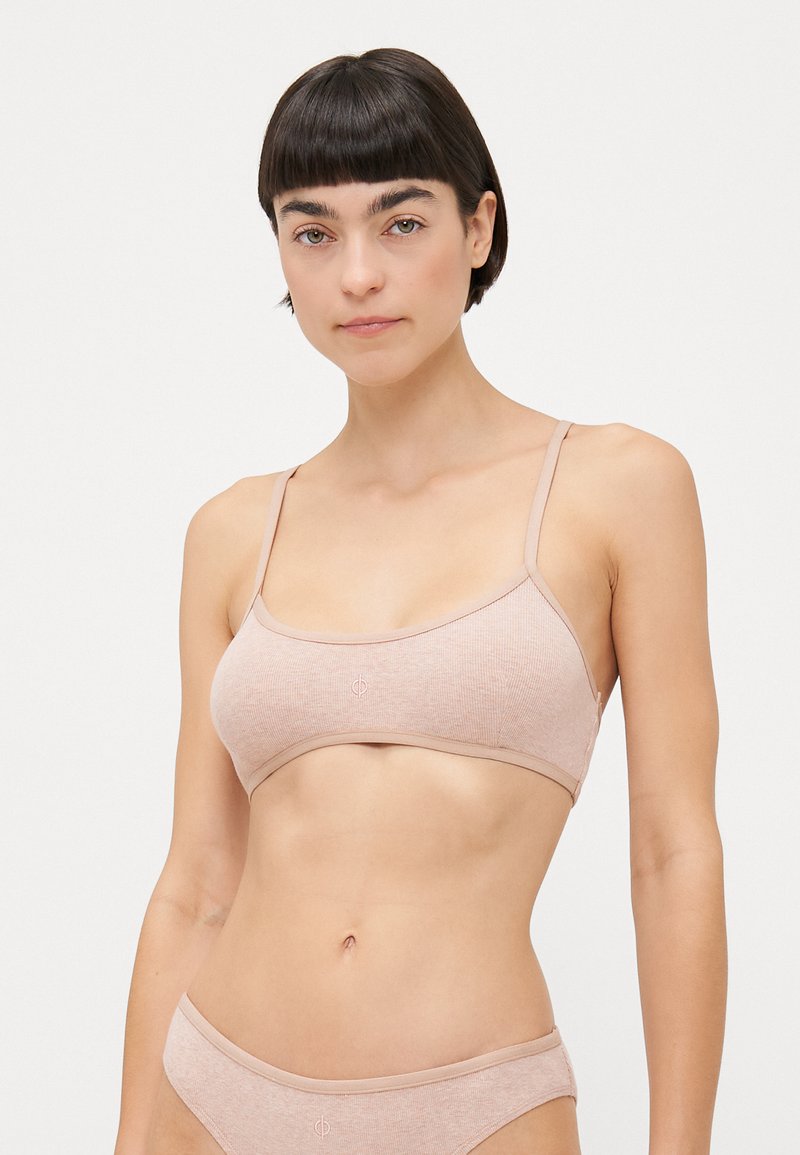 Light pink bralette with thin straps, made of soft ribbed fabric. Features a seamless design and subtle logo on the front.