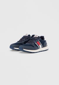 Ναυτικά μπλε αθλητικά παπούτσια με υλικά από δίχτυ και σουέντ, με κόκκινες και λευκές ρίγες, στρογγυλή μύτη και ανθεκτική καουτσούκ σόλα.