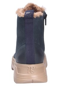 Botín de cuero navy con un collar forrado de piel, cremallera expuesta y suela de goma beige con acentos texturizados y un logo.