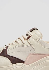 Sneaker chunky con una toma in pelle crema, dettagli marroni e rosa, sovrapposizioni testurizzate e lacci piatti. Presenta una suola ammortizzata.