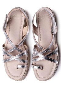 Sandalias destalonadas con correas metálicas plateadas y una suela beige. Cuentan con una cuña estilo esparto y una plantilla suave y texturizada.