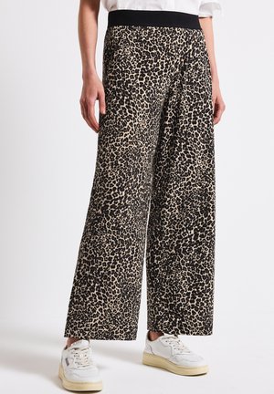 Wide-leg pants in a leopard print pattern, featuring a black elastic waistband. Fabric texture appears soft, complemented with white sneakers.