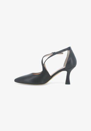 Scarpa da donna in pelle nera con tacco alto, punta appuntita, cinturini incrociati e tacco curvo di altezza media, mostrata di profilo.