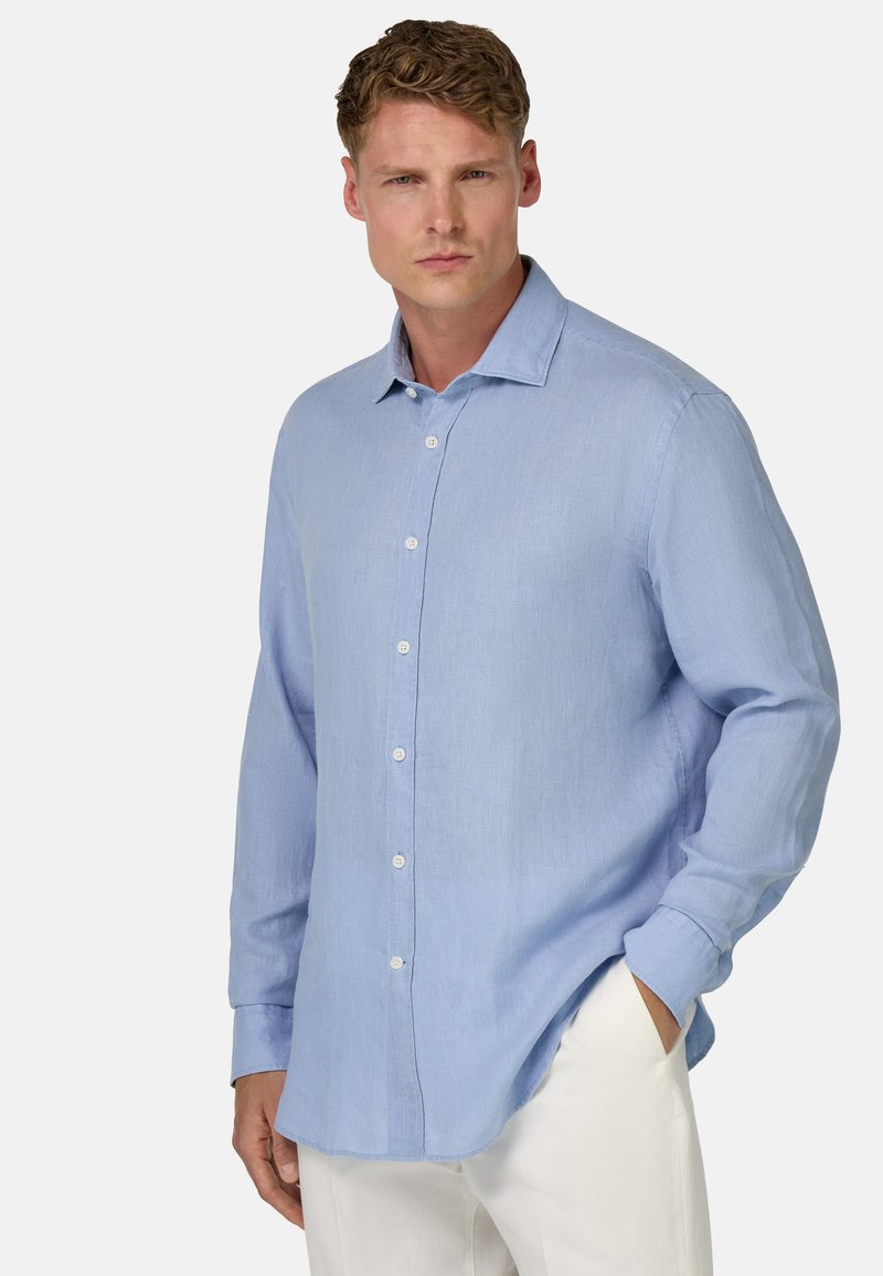 Světle modrá lněná košile s dlouhými rukávy, skládacím límečkem a pěti viditelnými knoflíky vpředu. Měkká textura a uvolněný střih.