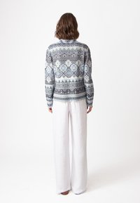 Zilgnu piedurkņu svītrota džemperis zili, pelēki un balti toņi ar sarežģītām zīmēm. Kombinēts ar baltām platām biksēm.