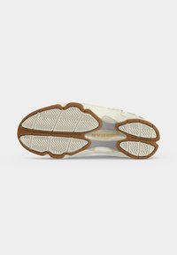 Semelle d’une chaussure de sport blanc et marron avec une bande de roulement texturée et le marquage « JORDAN » en beige sur la section médio-pied.