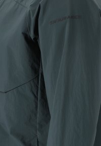 Wasserabweisende Jacke aus dunkelgrünem Nylon, mit glatter Textur, minimalistischem Design und "ENDURANCE"-Logo am Ärmel.