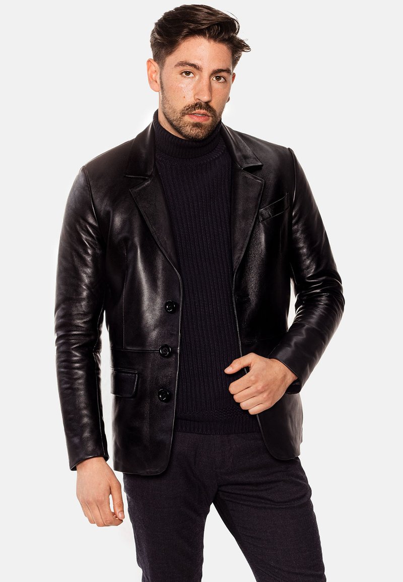 Blazer de cuero negro con un diseño entallado, que cuenta con solapa muesca, tres botones y un bolsillo en el pecho. Textura suave.