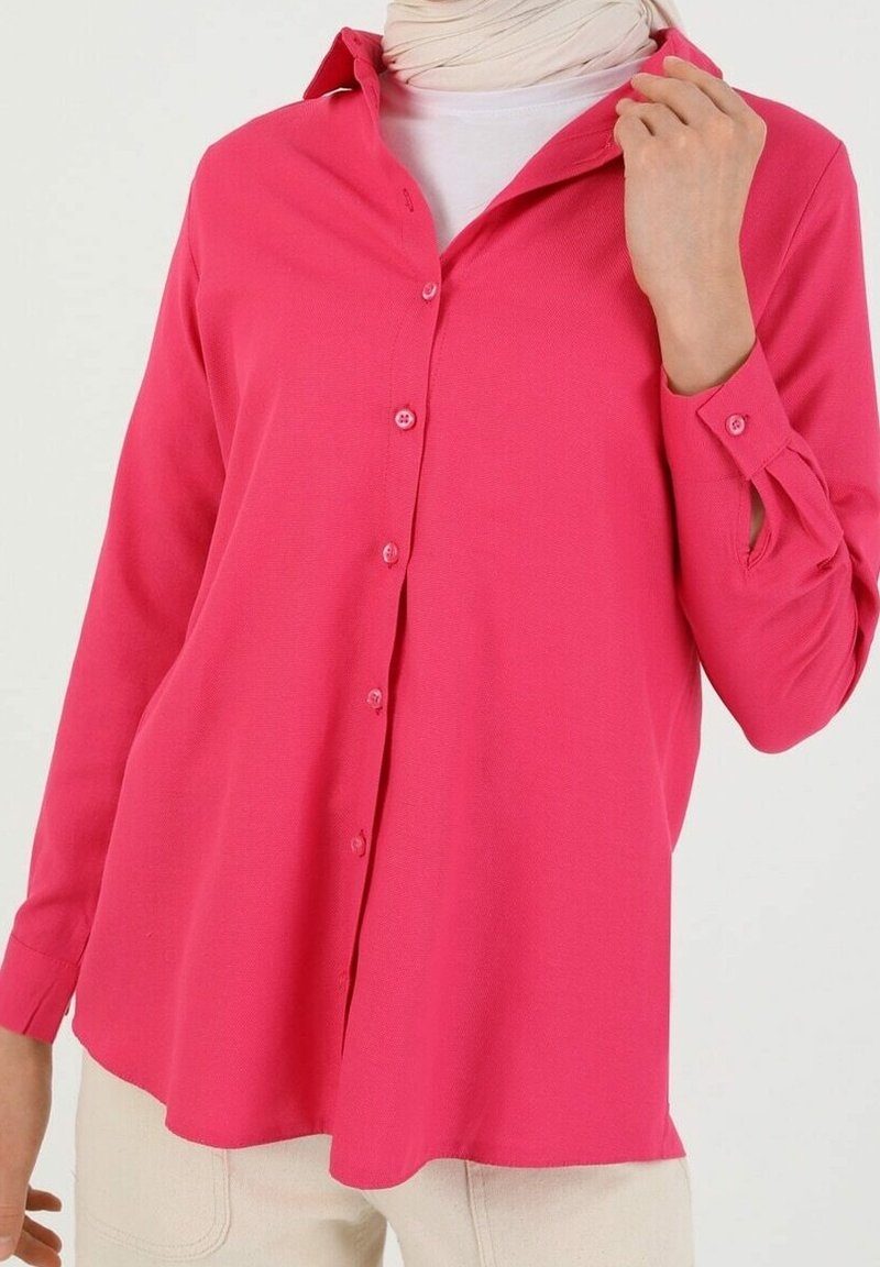 Chemise rose à boutons en tissu lisse, avec manches longues munies de poignets boutonnés et coupe décontractée.