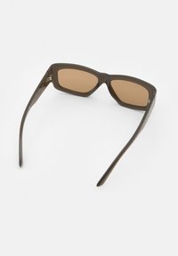 Ruske plastične sunčane naočale s geometrijskim dizajnom okvira i smeškastim staklima. Imaju uske drške. Minimalni ukrasi, mat površina.