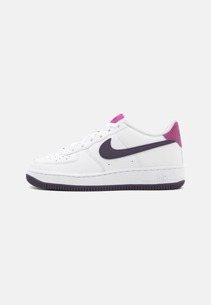 Baskets blanches Nike Air Force 1 avec logo swoosh noir, semelle noire, languette rose au talon et étiquette rose sur la languette, vues de côté extérieur.