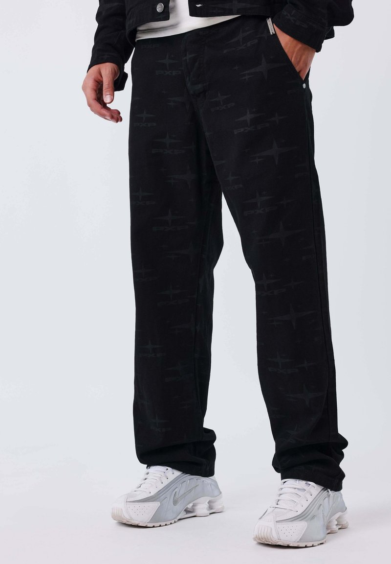 Pantaloni neri con un sottile motivo geometrico, dotati di tasche laterali e un design a gamba dritta, abbinati a scarpe sportive bianche.