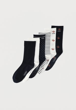 Six paires de chaussettes montantes noires et blanches avec différents motifs, y compris des rayures, des pois et des dessins floraux, disposées en rangée.