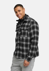 Sorte og hvide ternede flannel skjorte med krave, frontknaplukning, to brystlommer og lange ærmer. Glat tekstur med rutet mønster.